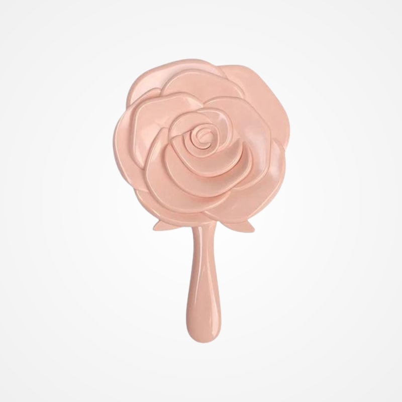 Miroir de poche rose posé sur une coiffeuse